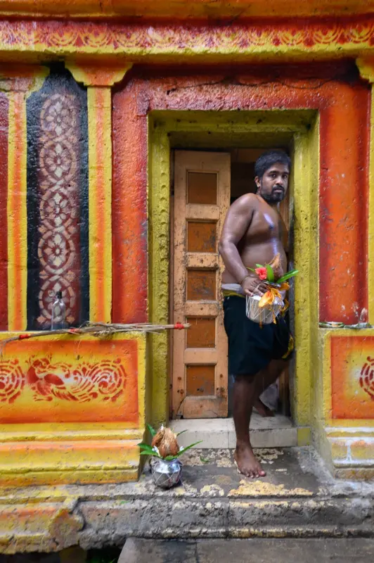 Pusari walking out of the side entrance to the chamber of Selva Sannithi Murugan Temple - Jaffna, Sri Lanka
