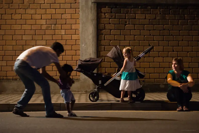 A father picking up a child while another family looks on - Gangarama Road, Colombo, Sri Lanka