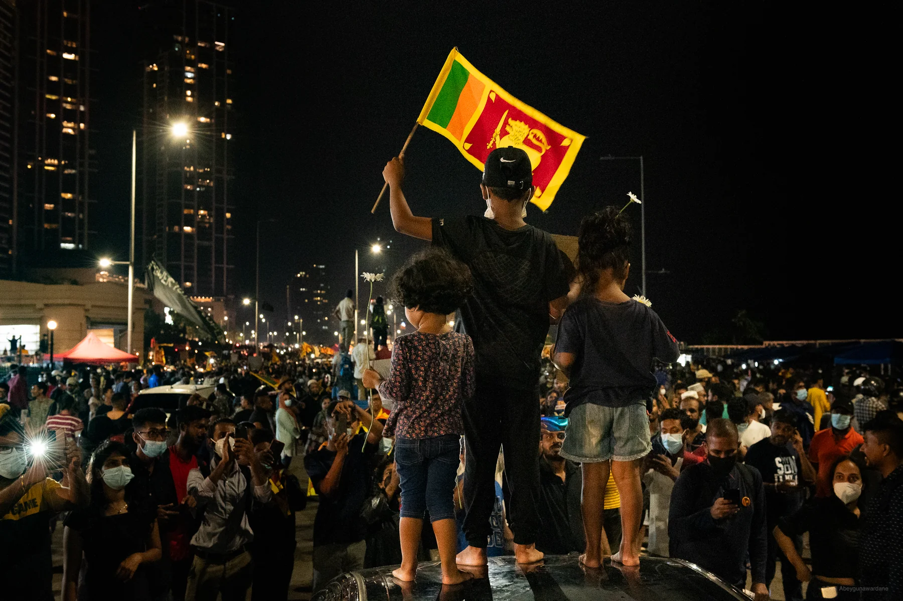 Children standing on top of a car holding the Sri Lankan national flag and flowers at the 2022 Sri Lankan protests and uprising - Galle Face, Sri Lanka
